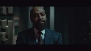 Movie still from “Infinite” (2021), directed by Antoine Fuqua – A man in a suit and tie looking at the camera; Close Up shot, Low angle