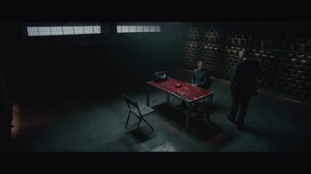 Movie still from “Infinite” (2021), directed by Antoine Fuqua – A table and chair in a room with a brick wall; Wide shot, High angle
