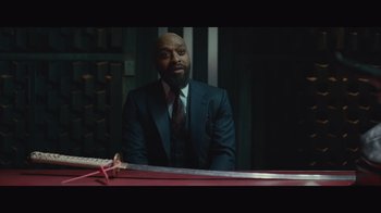 Movie still from “Infinite” (2021), directed by Antoine Fuqua – A man sitting at a table in a suit and tie; Medium shot, Over the shoulder angle