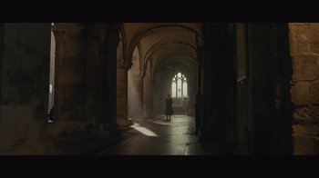 Movie still from “Infinite” (2021), directed by Antoine Fuqua – A person standing in a room with arches and a window; Extreme Wide shot, Low angle