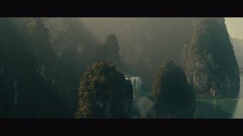 Movie still from “Infinite” (2021), directed by Antoine Fuqua – A view of a waterfall in the middle of a forest; Extreme Wide shot, High angle