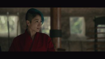Movie still from “Infinite” (2021), directed by Antoine Fuqua – A woman with blue hair sitting in front of a wooden pole; Close Up shot, Over the shoulder angle