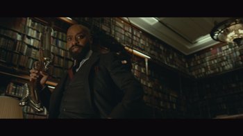 Movie still from “Infinite” (2021), directed by Antoine Fuqua – A man standing in a room with a bunch of bookshelves; Medium shot, Low angle
