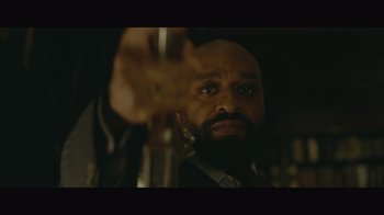Movie still from “Infinite” (2021), directed by Antoine Fuqua – A man in a suit and tie holding a glass; Extreme Close Up shot, Low angle