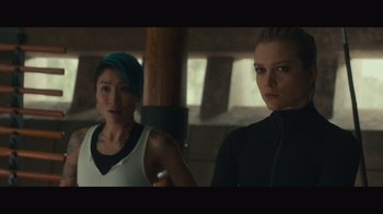 Movie still from “Infinite” (2021), directed by Antoine Fuqua – Two women standing next to each other in front of a wooden pole; Medium shot, Low angle