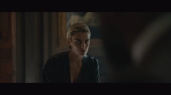 Movie still from “Infinite” (2021), directed by Antoine Fuqua – A woman sitting in front of a painting; Close Up shot, Over the shoulder angle