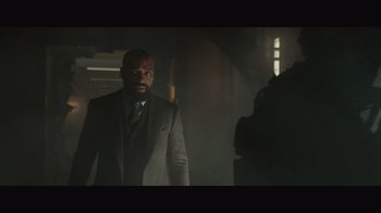 Movie still from “Infinite” (2021), directed by Antoine Fuqua – A man in a suit and tie standing in a dark room; Medium shot, Low angle