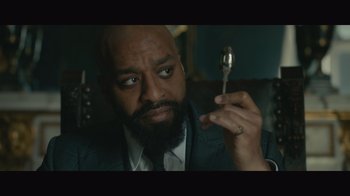 Movie still from “Infinite” (2021), directed by Antoine Fuqua – A man in a suit and tie holding a spoon; Close Up shot, Low angle