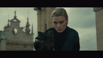 Movie still from “Infinite” (2021), directed by Antoine Fuqua – A woman is holding a gun in a city; Close Up shot, Low angle