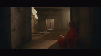 Movie still from “Infinite” (2021), directed by Antoine Fuqua – A monk sitting on the ground in front of an archway; Extreme Wide shot, Low angle
