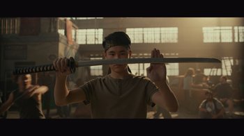 Movie still from “Infinite” (2021), directed by Antoine Fuqua – A young man holding a baseball bat over his head; Medium shot, Low angle