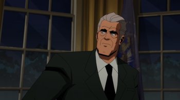 Movie still from “Injustice” (2021), directed by Matt Peters – An older man in a suit and tie in front of a window; Medium shot, Over the shoulder angle