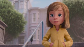 Movie still from “Inside Out” (2015), directed by Pete Docter – A girl in a yellow jacket standing in front of a building; Medium shot, Low angle