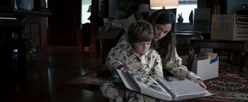 Movie still from “Insidious” (2010), directed by James Wan – A woman and a boy in pajamas looking at an open book; Medium shot, High angle