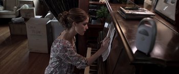 Movie still from “Insidious” (2010), directed by James Wan – A woman cleaning a piano with a cloth; Medium shot, High angle