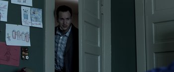 Movie still from “Insidious” (2010), directed by James Wan – A man standing in front of an open door; Medium shot, Low angle