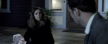 Movie still from “Insidious” (2010), directed by James Wan – A woman sitting on the ground in front of a man; Medium shot, Over the shoulder angle