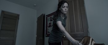 Movie still from “Insidious” (2010), directed by James Wan – A woman standing in front of a wall holding onto something; Medium shot, Low angle