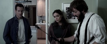 Movie still from “Insidious” (2010), directed by James Wan – A woman standing in front of a man holding a sword; Medium shot, Over the shoulder angle