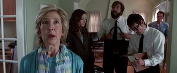 Movie still from “Insidious” (2010), directed by James Wan – Three people standing in a living room , one of whom is holding a purse; Close Up shot, Over the shoulder angle