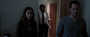 Movie still from “Insidious” (2010), directed by James Wan – A man and a woman standing in front of a door; Medium shot, Over the shoulder angle