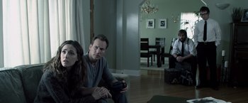 Movie still from “Insidious” (2010), directed by James Wan – A man and a woman sitting on a couch in a living room; Medium shot, Over the shoulder angle