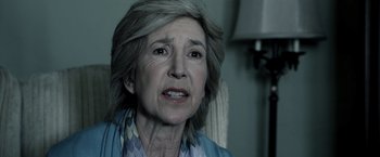 Movie still from “Insidious” (2010), directed by James Wan – An older woman with gray hair looking at the camera; Close Up shot, Over the shoulder angle