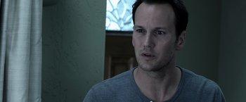 Movie still from “Insidious” (2010), directed by James Wan – A person wearing a gray t - shirt; Close Up shot, Over the shoulder angle