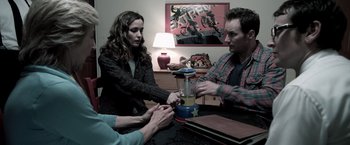 Movie still from “Insidious” (2010), directed by James Wan – A group of people gathered around a blender; Medium shot, Over the shoulder angle