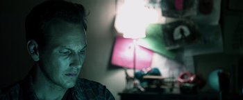 Movie still from “Insidious” (2010), directed by James Wan – A man sitting in front of a lamp in a living room; Close Up shot, Low angle