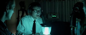 Movie still from “Insidious” (2010), directed by James Wan – A man wearing headphones looking at a lamp; Medium shot, High angle