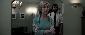 Movie still from “Insidious” (2010), directed by James Wan – An older woman standing next to a younger man; Medium shot, Over the shoulder angle