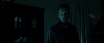Movie still from “Insidious” (2010), directed by James Wan – A man standing in the dark in front of a mirror; Close Up shot, Low angle