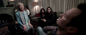 Movie still from “Insidious” (2010), directed by James Wan – A group of people sitting around a living room together; Medium shot, Over the shoulder angle
