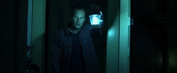 Movie still from “Insidious” (2010), directed by James Wan – A man standing in front of a wall holding a flashlight; Medium shot, Low angle