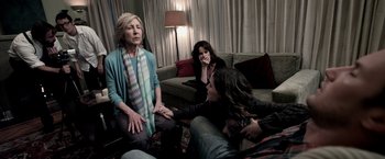 Movie still from “Insidious” (2010), directed by James Wan – A group of people sitting in a living room; Medium shot, Over the shoulder angle