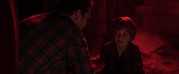 Movie still from “Insidious” (2010), directed by James Wan – A man and a boy are sitting in a dark room; Medium shot, Over the shoulder angle