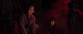 Movie still from “Insidious” (2010), directed by James Wan – A man and a boy sitting on the ground; Medium shot, High angle