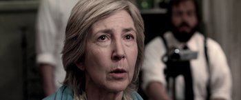Movie still from “Insidious” (2010), directed by James Wan – An older woman looking at the camera with an intense look on her face; Close Up shot, Over the shoulder angle