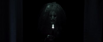 Movie still from “Insidious” (2010), directed by James Wan – A woman holding a lit candle in a dark room; Close Up shot, High angle