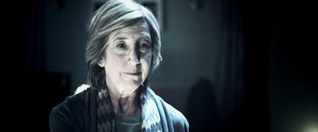 Movie still from “Insidious” (2010), directed by James Wan – An older woman wearing a scarf looking at the camera; Close Up shot, Over the shoulder angle