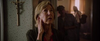 Movie still from “Insidious: The Last Key” (2018), directed by Adam Robitel – An older woman holding her hand up to her ear; Close Up shot, Over the shoulder angle