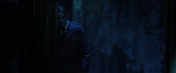 Movie still from “Insidious: The Last Key” (2018), directed by Adam Robitel – A man in a suit and tie standing next to a door; Medium shot, Over the shoulder angle