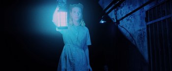 Movie still from “Insidious: The Last Key” (2018), directed by Adam Robitel – A woman holding a lantern in a dark room; Medium shot, Low angle