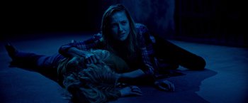 Movie still from “Insidious: The Last Key” (2018), directed by Adam Robitel – A woman laying on the ground next to a dog; Medium shot, High angle