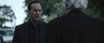 Movie still from “Insidious: The Red Door” (2023), directed by Patrick Wilson – A man in a black suit and a man in a black suit; Close Up shot, Over the shoulder angle