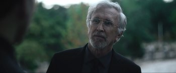 Movie still from “Insidious: The Red Door” (2023), directed by Patrick Wilson – An older man wearing a black suit and glasses; Close Up shot, Over the shoulder angle