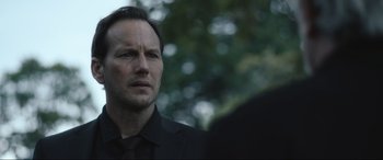 Movie still from “Insidious: The Red Door” (2023), directed by Patrick Wilson – A person wearing a suit and tie; Close Up shot, Over the shoulder angle
