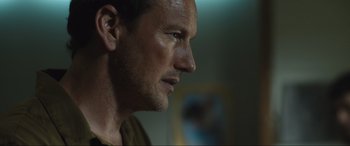 Movie still from “Insidious: The Red Door” (2023), directed by Patrick Wilson – A man's face in a dark room; Close Up shot, Over the shoulder angle