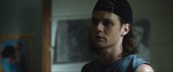 Movie still from “Insidious: The Red Door” (2023), directed by Patrick Wilson – A man with long brown hair wearing a black hat; Close Up shot, Over the shoulder angle